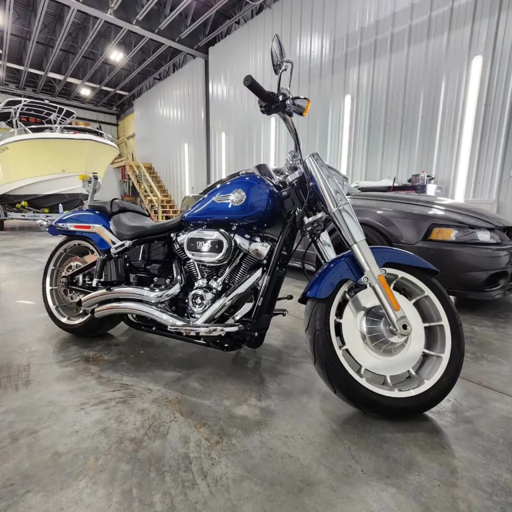 Blue and black Harley-Davidson cruiser motorcycle with chrome details parked in industrial garage.
