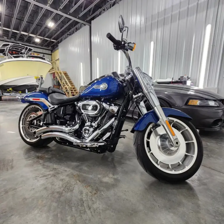 Blue and black Harley-Davidson cruiser motorcycle with chrome details parked in industrial garage.