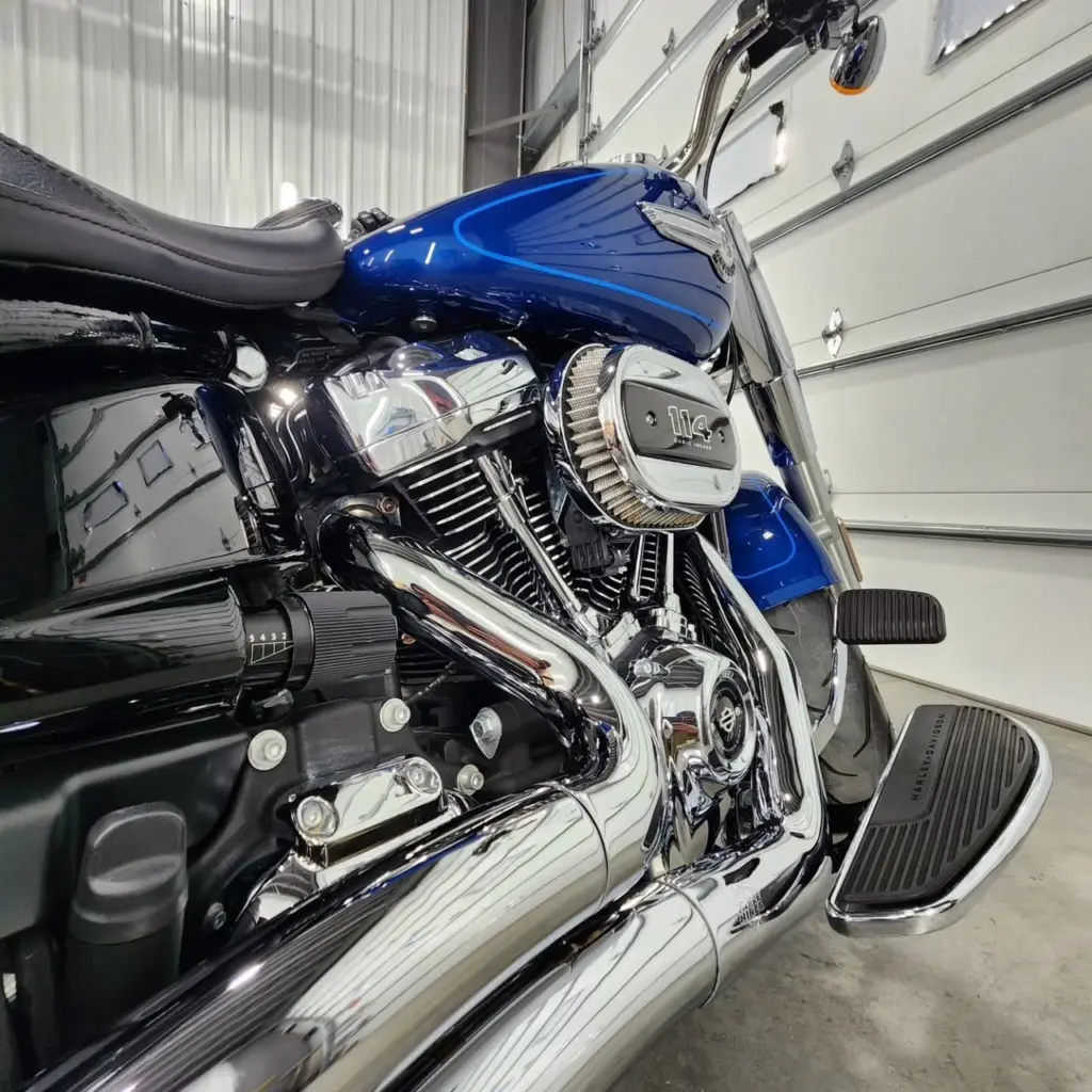 Close-up of a blue Harley-Davidson motorcycle engine and chrome components in a garage.