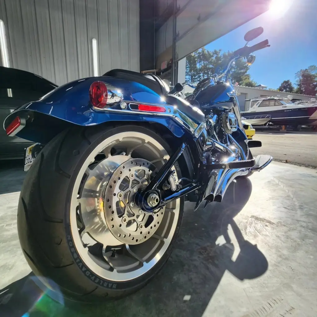 Blue Harley-Davidson motorcycle with chrome details and white-wall tire, parked in service bay.