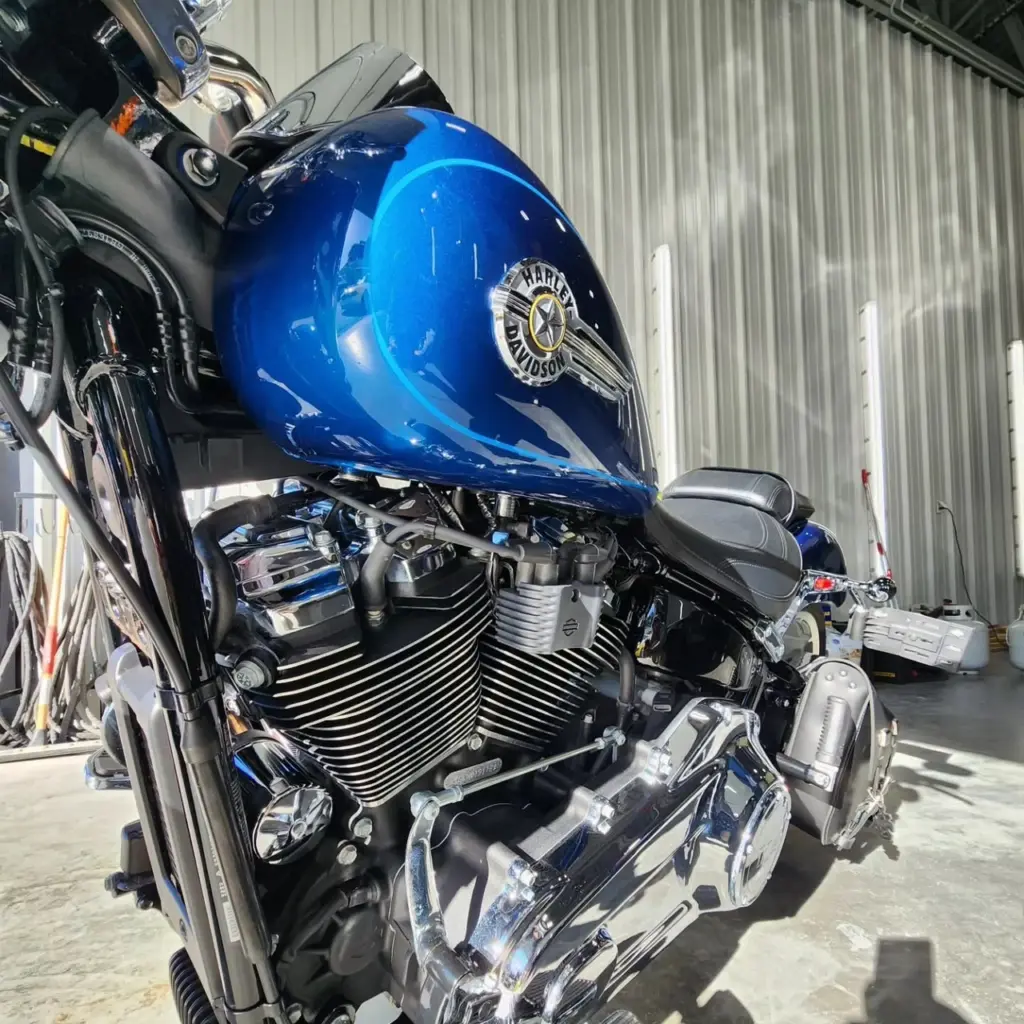 Blue Harley-Davidson motorcycle with chrome engine and finned cylinder head in garage setting.