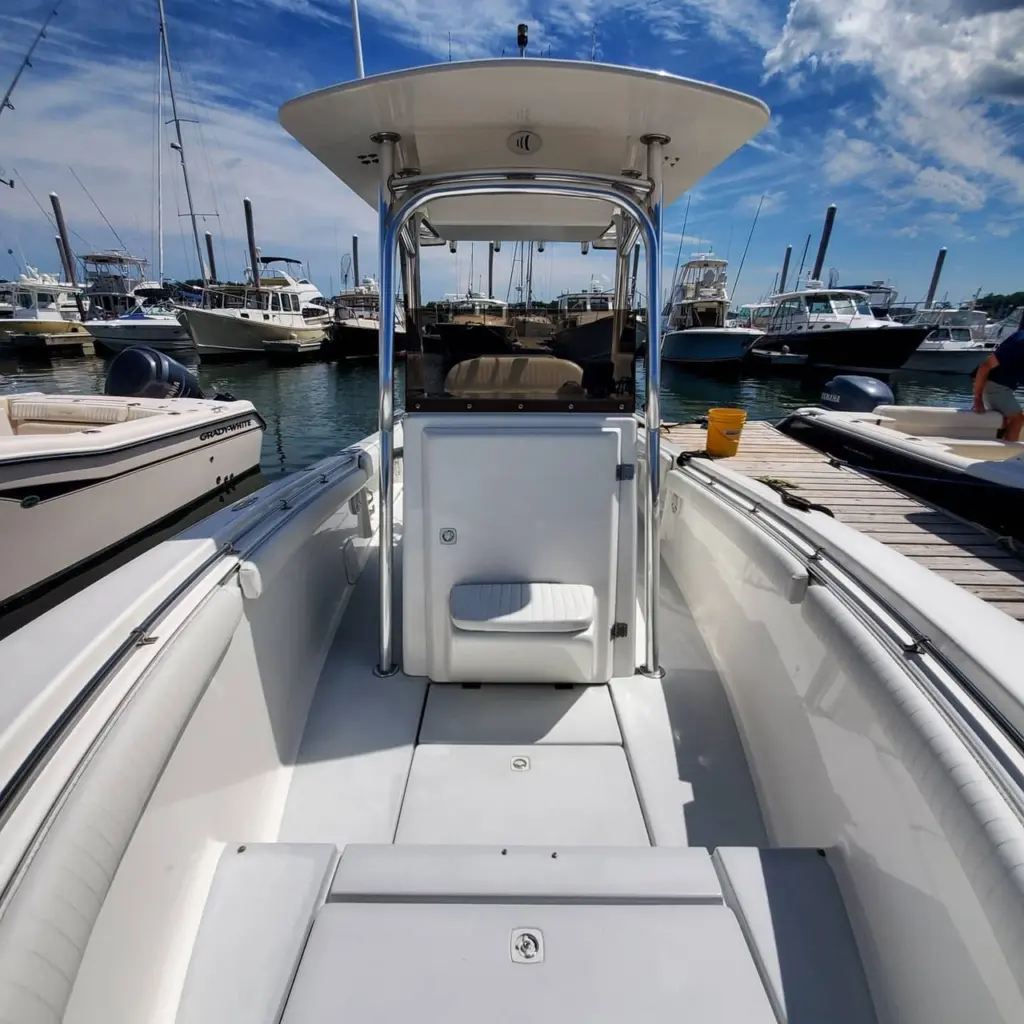 White center console boat with open cabin door and hardtop canopy, docked at Pembroke marina with other vessels in background.