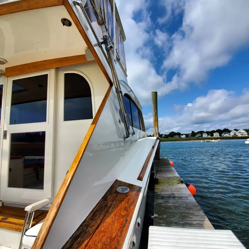 Boat cabin exterior showing cream-colored hull with wooden trim details, moored at dock in Pembroke.