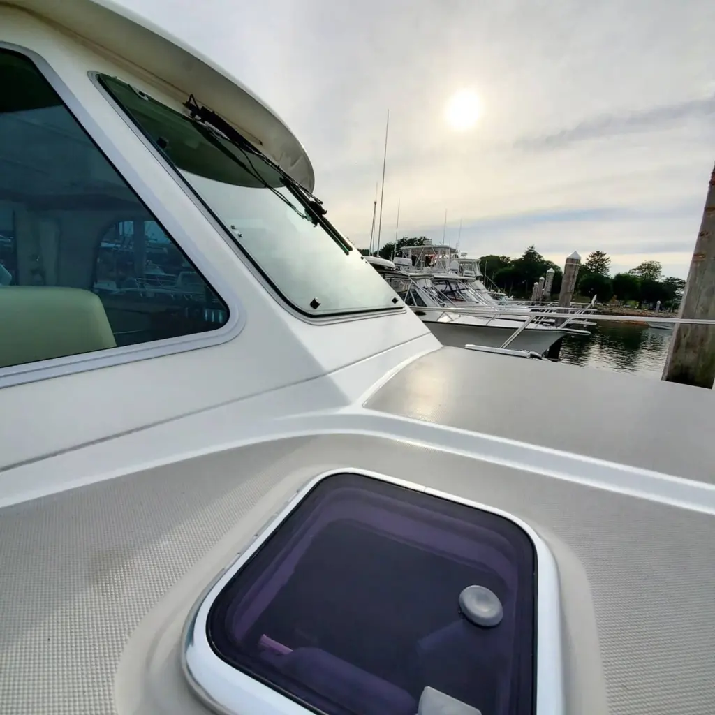 White boat cabin with open hatch and windshield, moored boats visible at Pembroke marina dock.