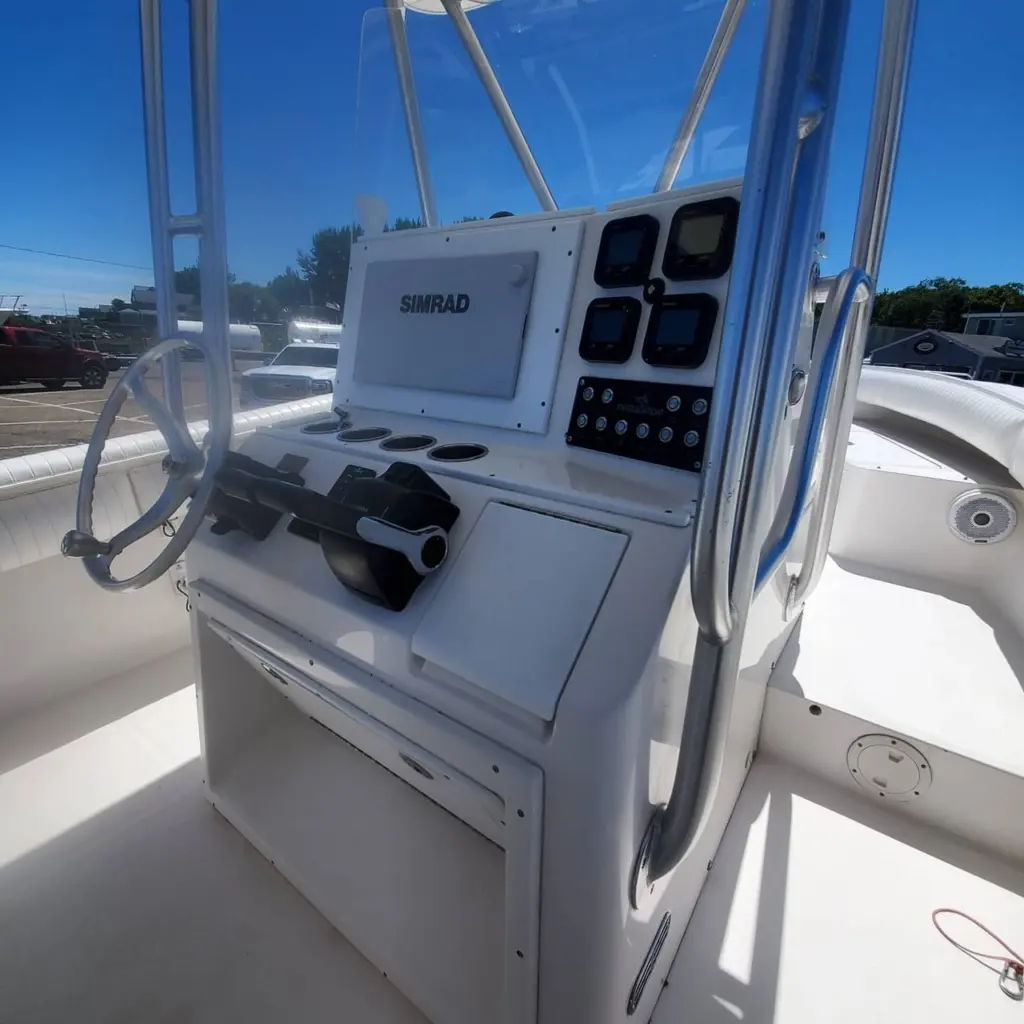 Boat console with Simrad navigation display, steering wheel, and instrument panel in bright sunlight.