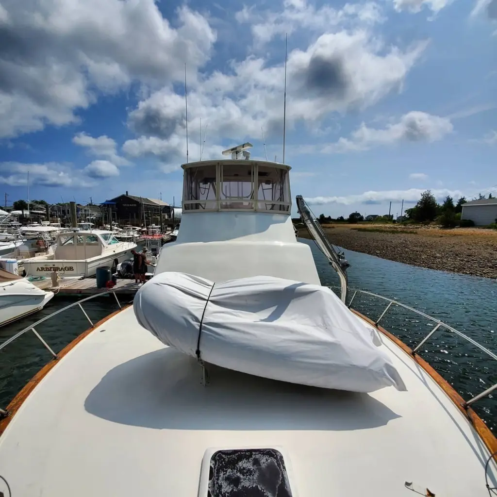 Forward deck of a white boat with covered tender, helm cabin visible, moored at Pembroke marina.