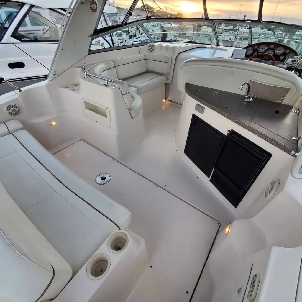 Interior view of boat galley with cream seating, black countertop, and display screen mounted on starboard side.