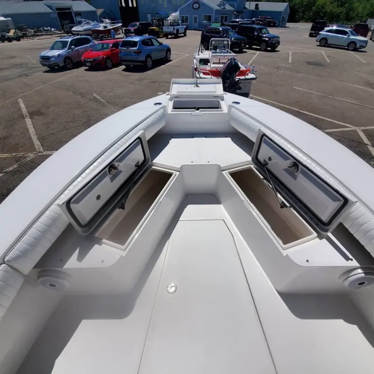 White boat interior viewed from bow, showing dual storage compartments with dark trim and center walkway.