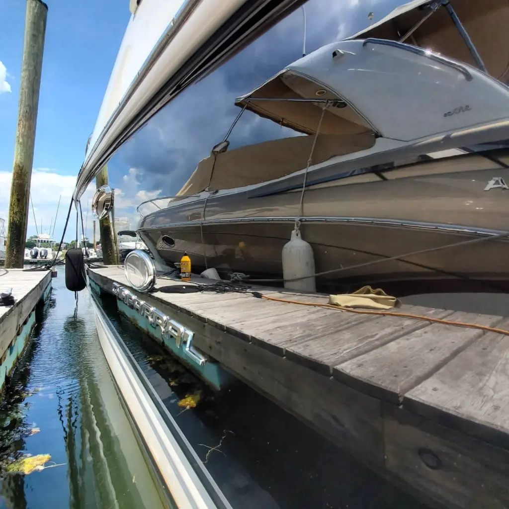 Multiple boats moored at a wooden dock with canvas covers and equipment visible along the waterfront.