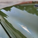 Close-up of a car hood with protective film applied, showing reflective surface and edge detail.
