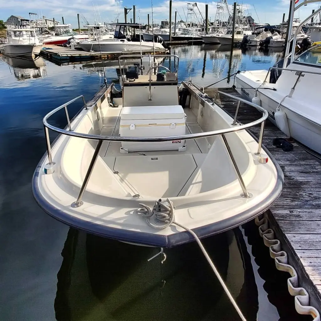 White center console fishing boat moored at Pembroke marina dock with multiple vessels visible in background.