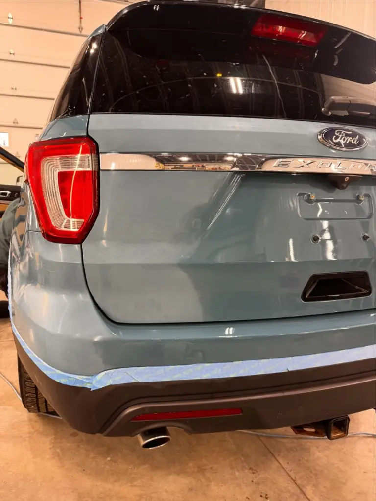 Rear quarter view of a gray Ford Explorer SUV showing taillight and rear bumper in a garage.