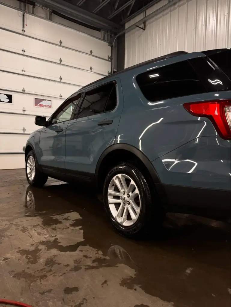 Gray compact SUV parked in garage with white overhead door, showing rear quarter panel and wheel detail.