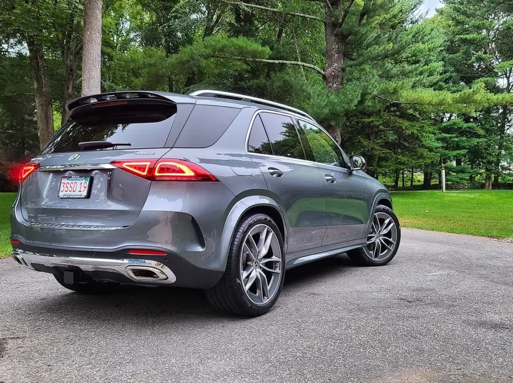 Gray Mercedes-Benz GLE SUV parked on driveway, rear three-quarter view showing taillights and wheels.