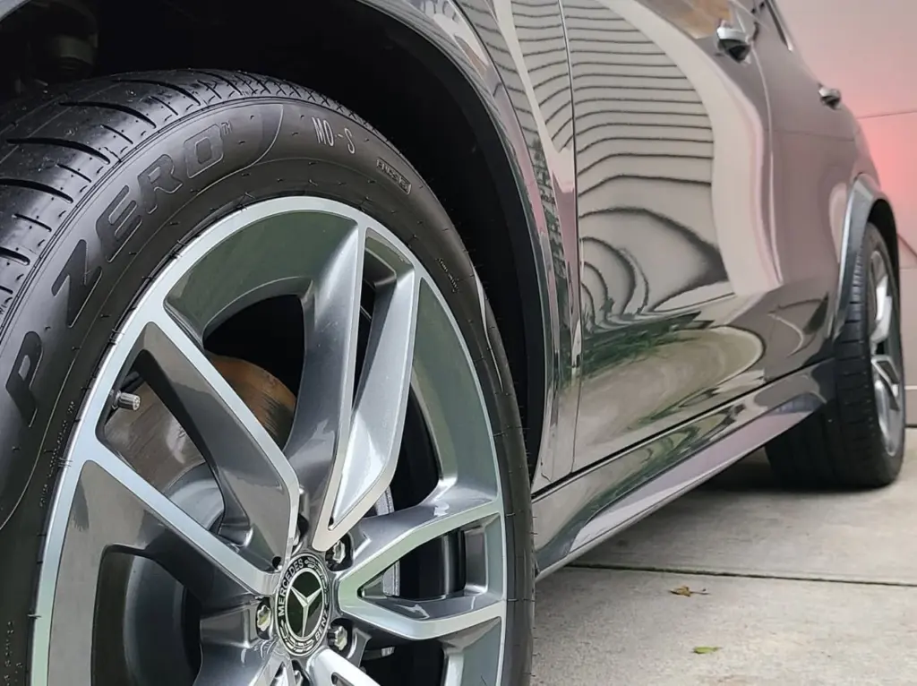 Close-up of a Mercedes-Benz alloy wheel and tire on a silver sedan, showing reflective finish and tread detail.