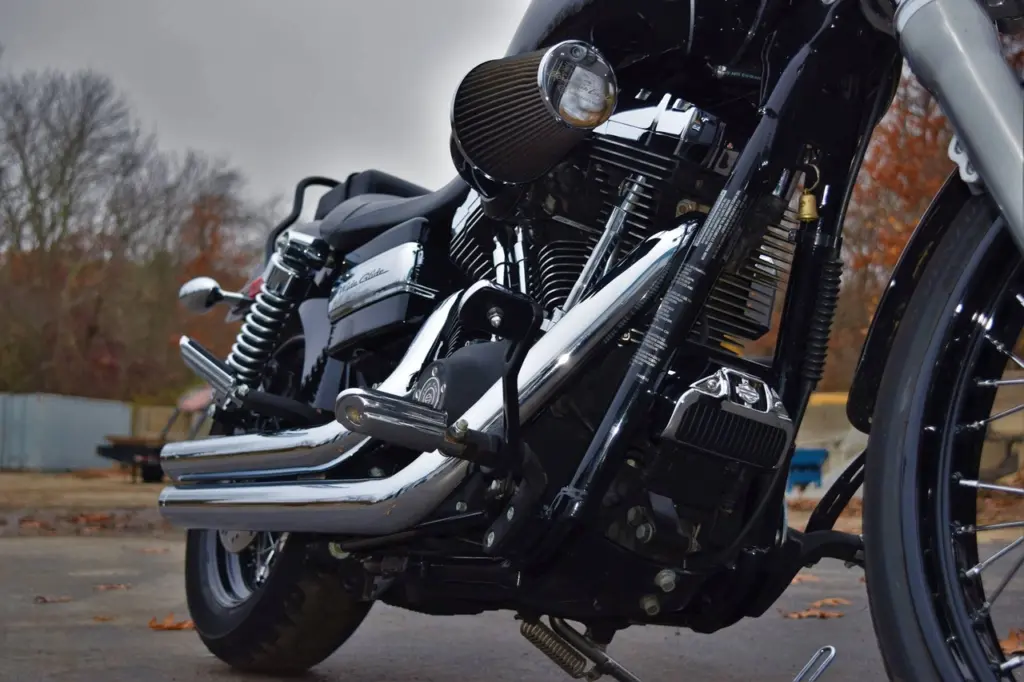 Close-up of a motorcycle engine with chrome finned cylinders and black fuel tank parked outdoors.