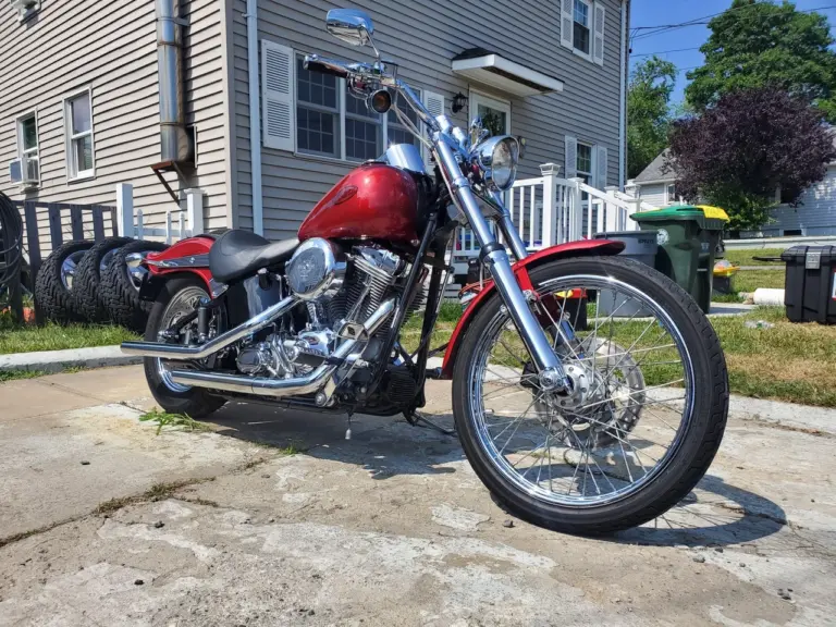 Red and black cruiser motorcycle with polished chrome details parked on residential street.