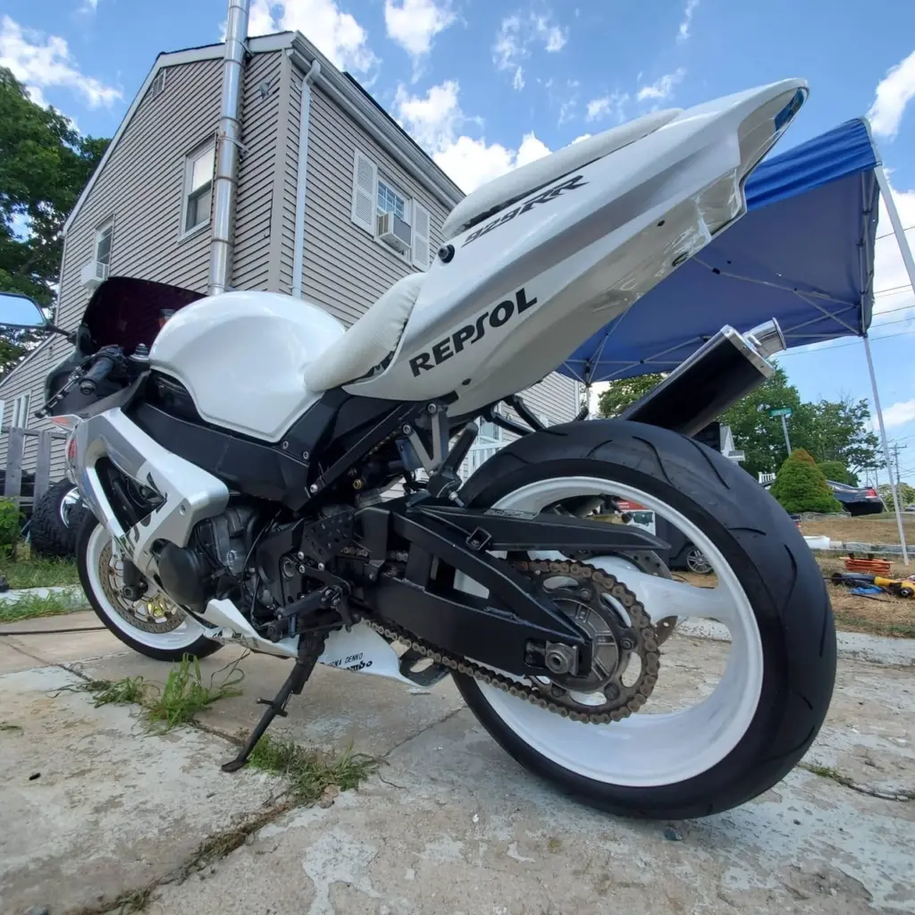 White and black motorcycle parked beside a white Repbol speedboat on a residential driveway in Pembroke.