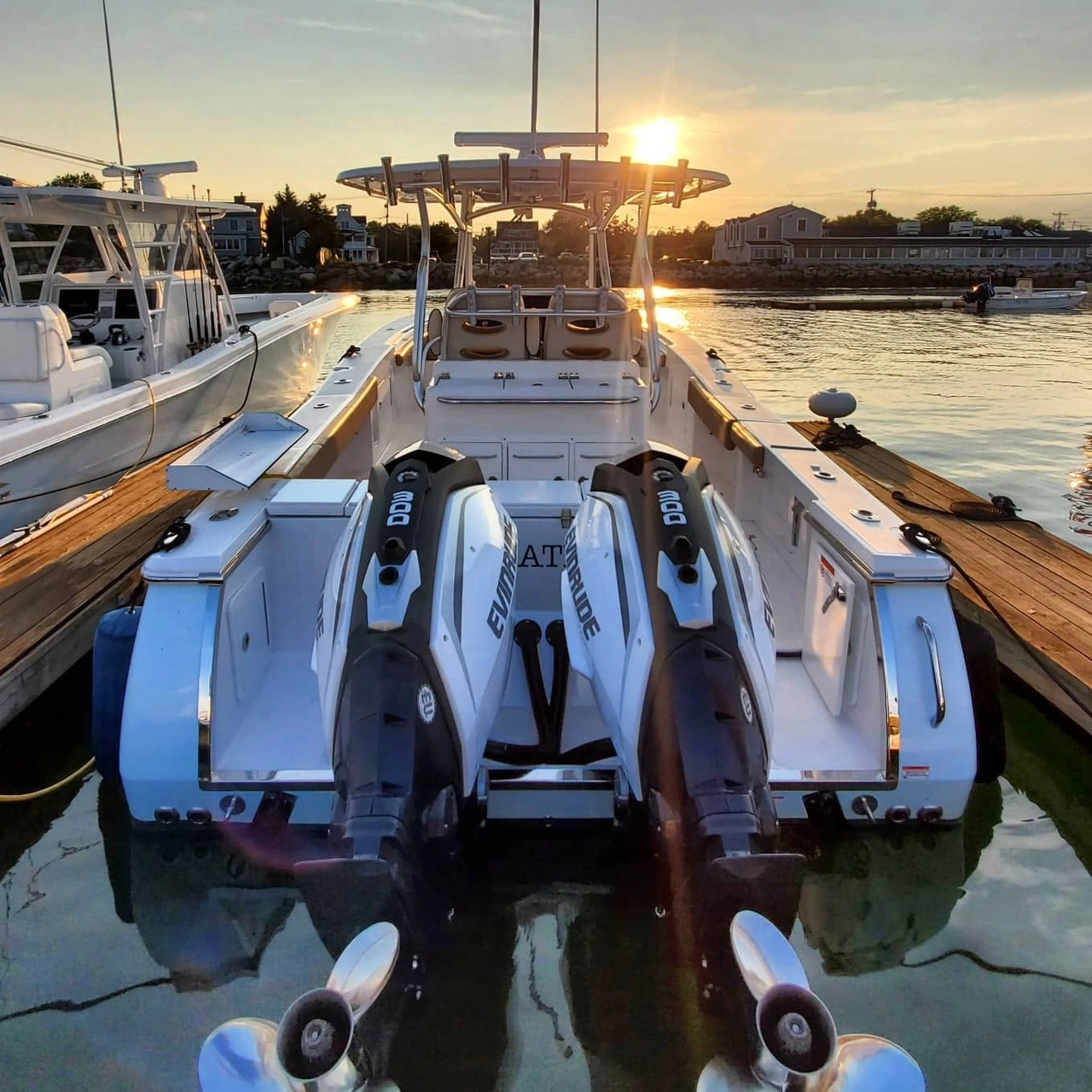 Center console boat with twin Evinrude jet skis moored at Pembroke dock at sunset.