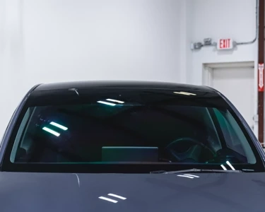 Close-up of a car's front windshield and hood during detailing service.